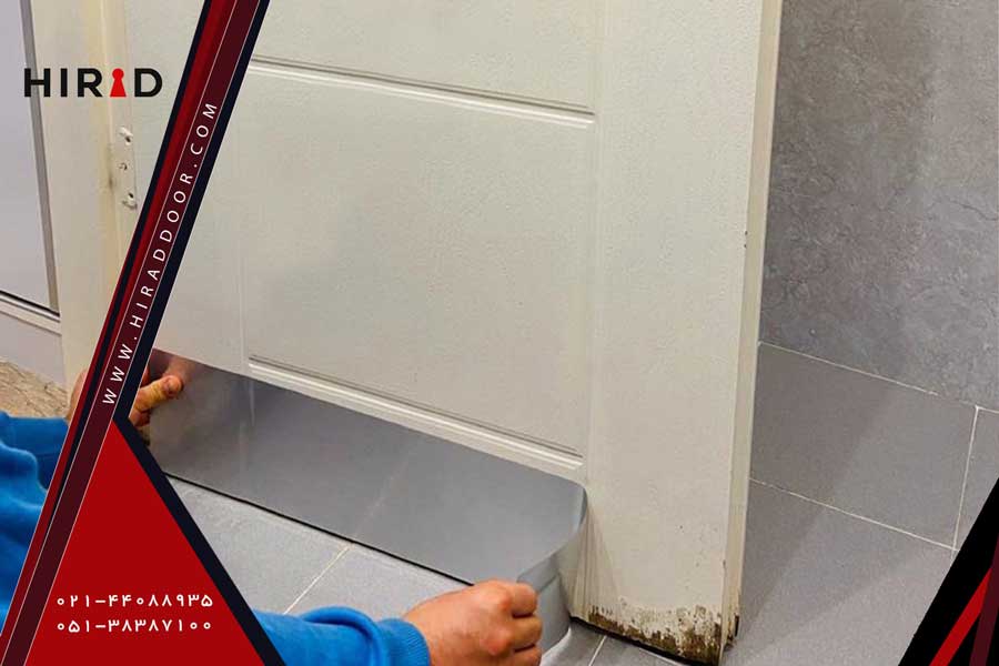 فردی در حال چسباندن ورق فلزی به پایی درب سرویسی برای جلوگیری از پوسیدگی درب